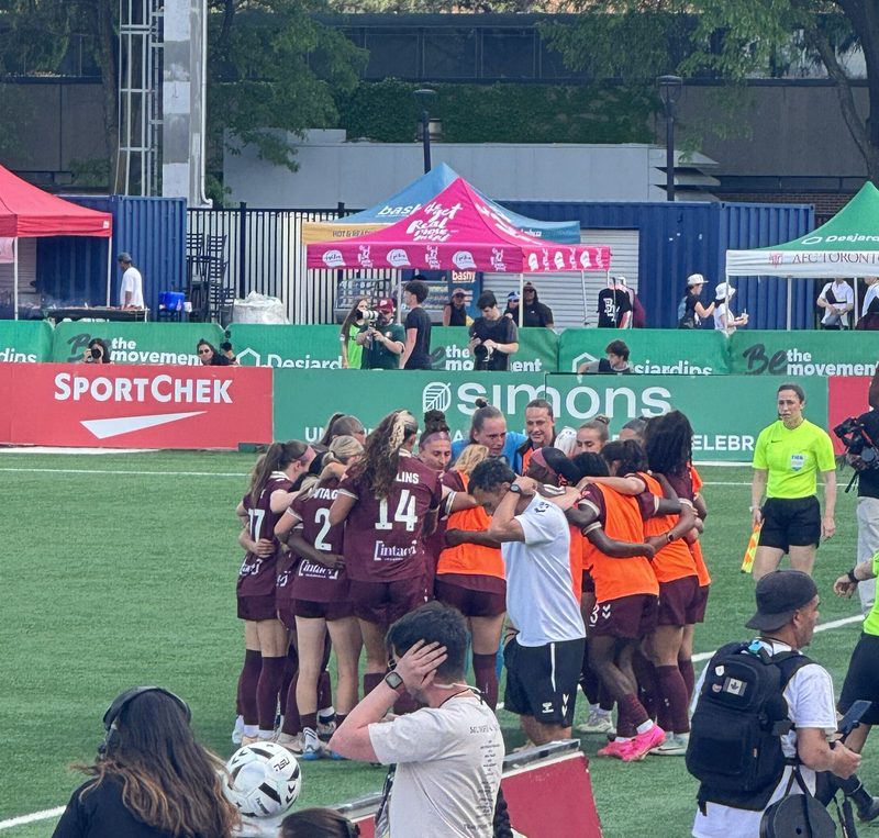 AFC Toronto players celebrating together on the pitch