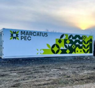 A branded Marcatus PEC container growing unit standing in a field at dusk